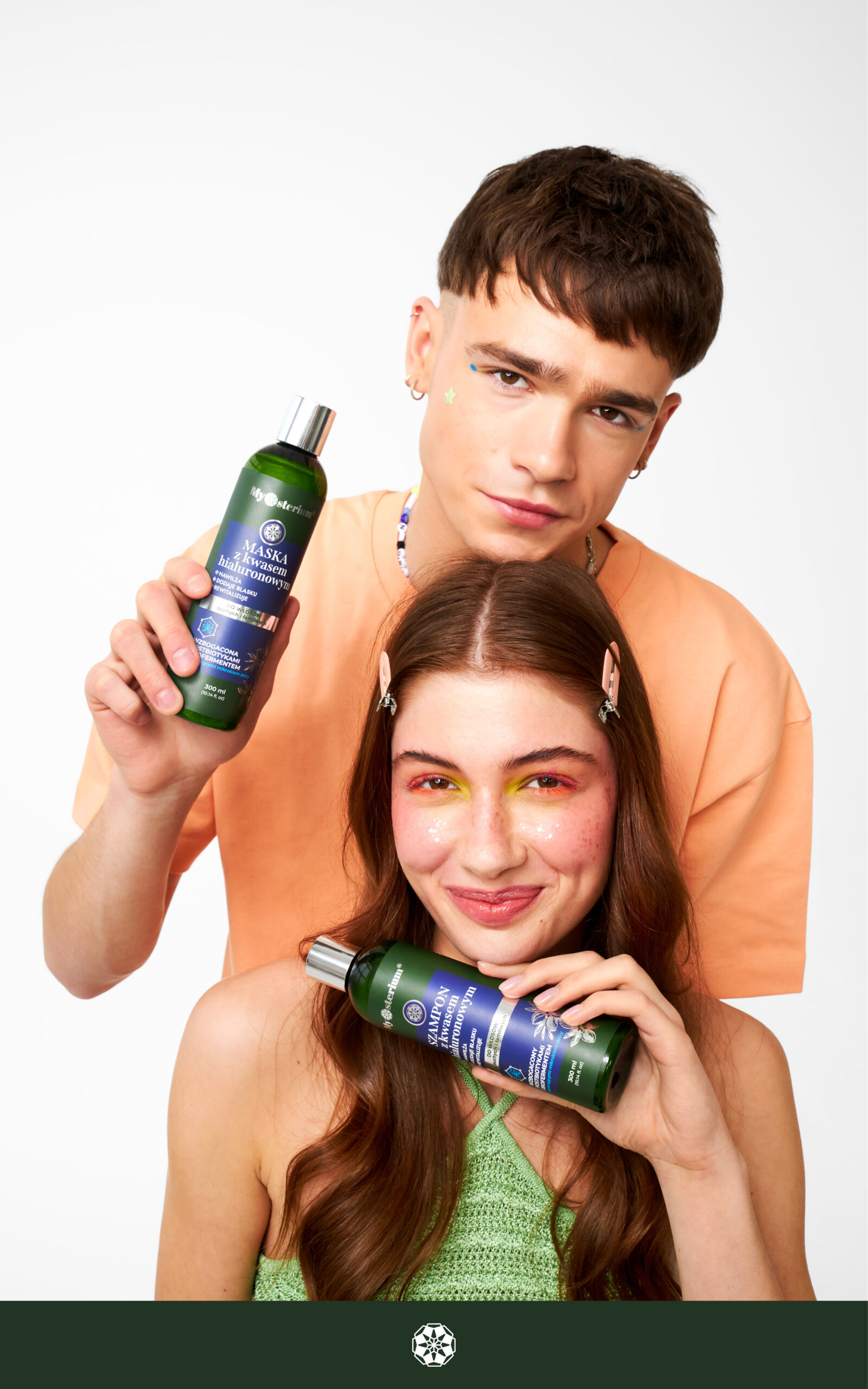Kobieta i mężczyzna prezentują kosmetyki do pielęgnacji włosów w zielonych butelkach.